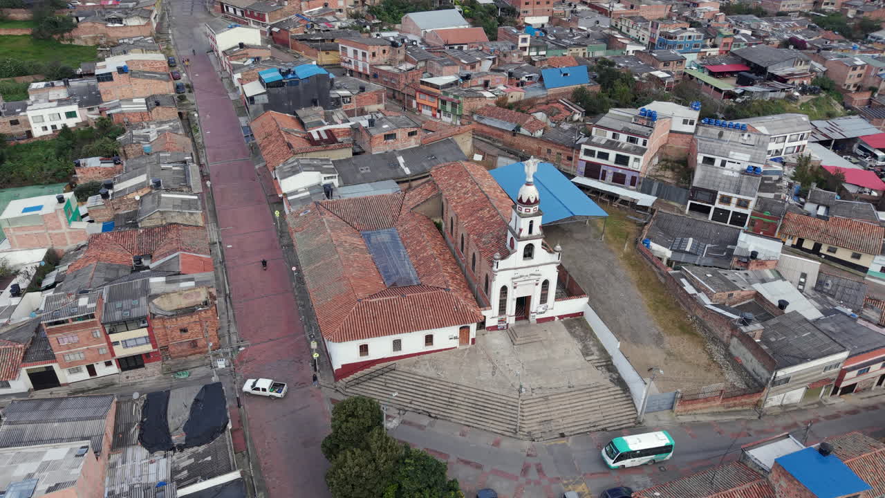 Drone video showcasing Parroquia Nuestra Señora De Los Dolores in Zipaquira, highlighting the church's architecture amidst vibrant town. Daytime lighting reveals intricate urban layout