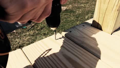 man using a drill to screw in a screw in slow motion