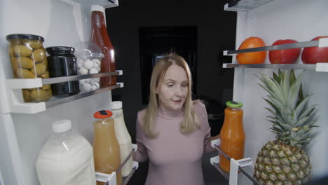 a woman eats sweets from the refrigerator. nighttime snacking and junk food