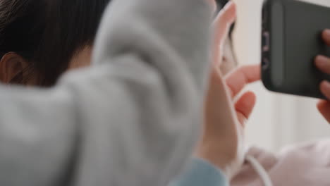 집에서 스마트폰을 사용하는 행복한 아시아 가족 어머니 어린 소녀 부모와 함께 엔터테인먼트를보고 터치 스크린 장치에서 게임을하고 온라인을 탐색하고 소파에서 함께 휴식을 취합니다 4k 영상