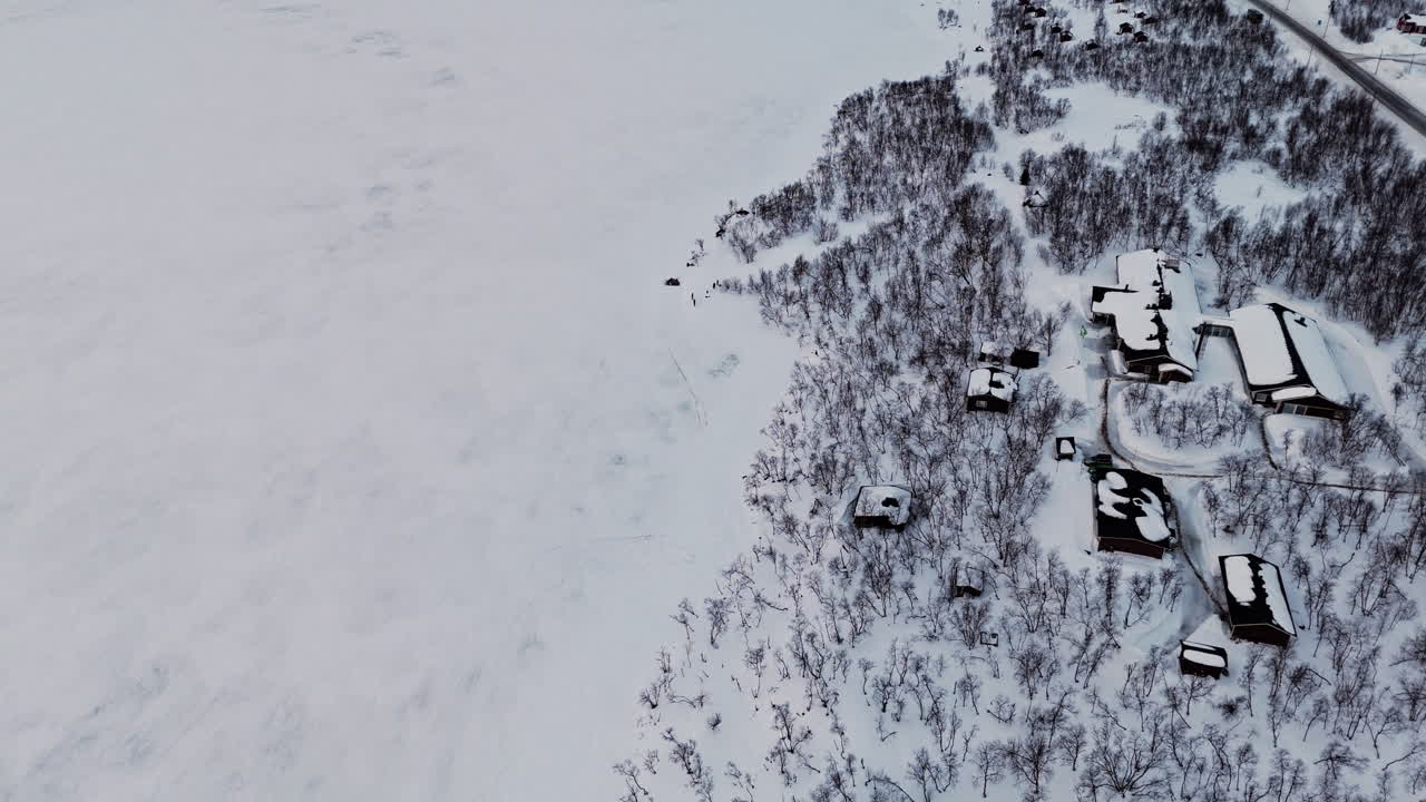 Frozen Kilpisjärvi landscape with snow-covered cabins and winter forest