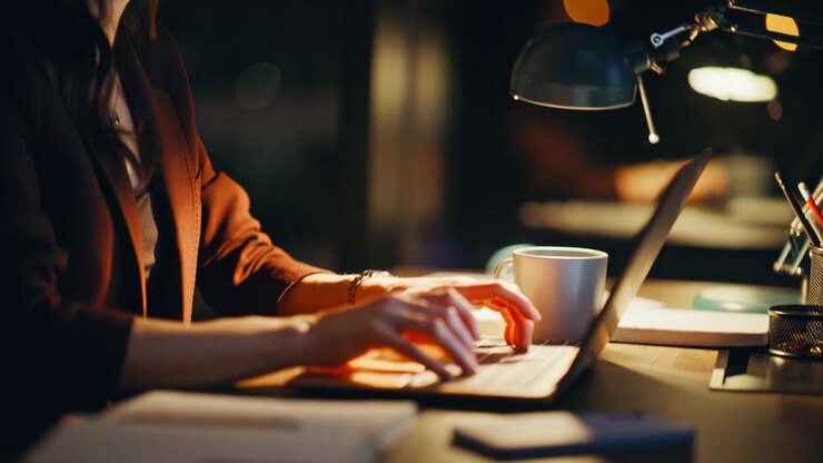 Late worker looking computer typing keyboard in office under lamp light closeup