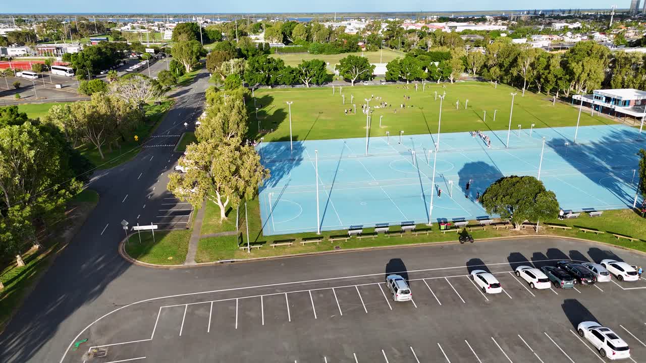 Drone footage captures netball courts and parking area under bright sunlight at Gold Coast Performance Centre