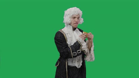 retrato de un caballero cortesano en traje vintage histórico negro y peluca, comiendo codiciosamente una hamburguesa con queso. joven posando en el estudio con fondo de pantalla verde. primer plano. cámara lenta lista 59.94fps