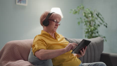 old woman in headphones with a tablet