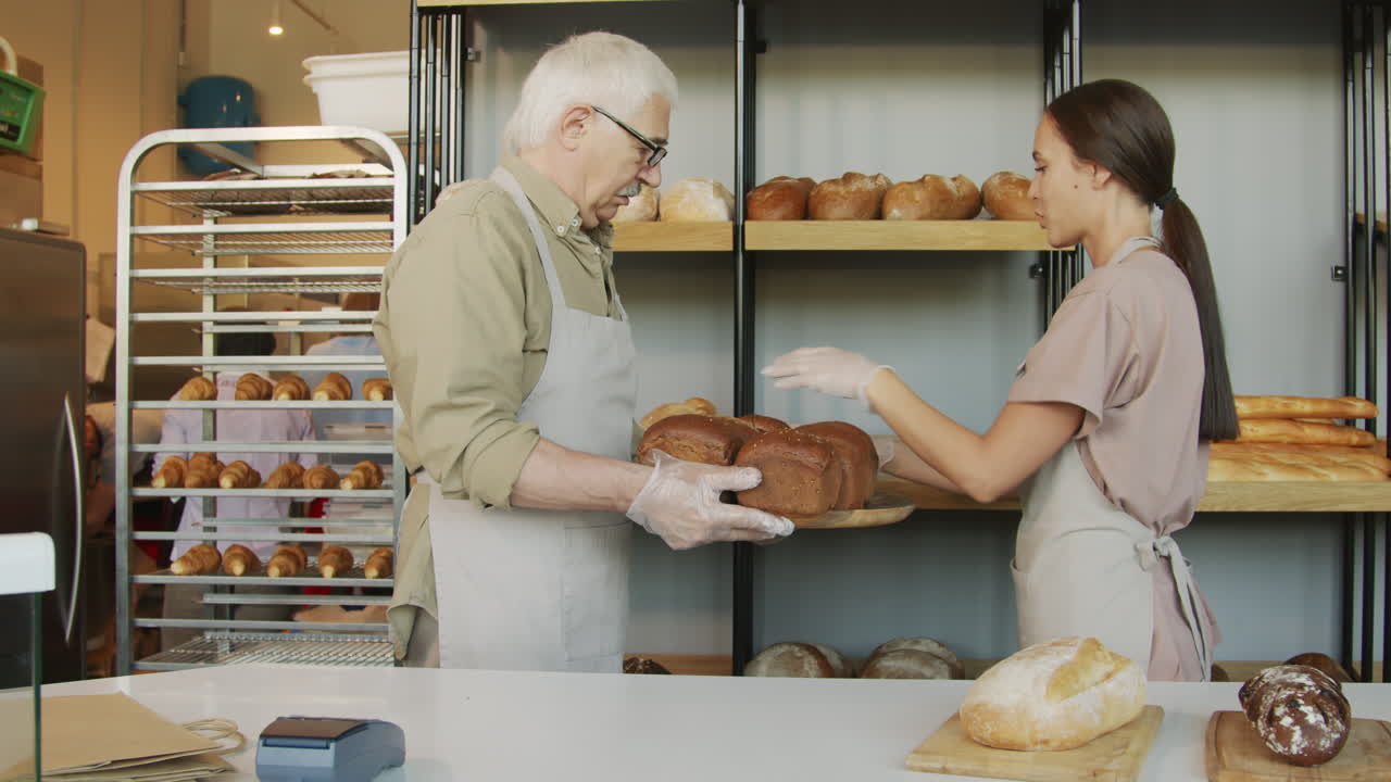 People Putting Freshly Baked Bread on Shelf in Bakery