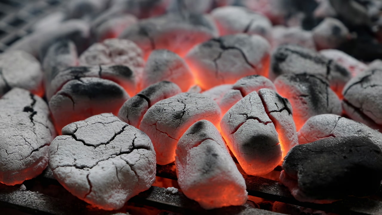 Glowing Charcoal Embers On Metal Grate, Closeup Showing Ashcoated Briquettes With Cracked Surfaces And Molten