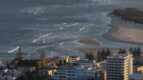 Drone-Costero-Sobre-Apartamentos-Junto-A-La-Playa-Con-Vistas-A-Las-Olas-Azules-Del-Océano-En-La-Ciudad-De-La-Costa-Australiana,-Paralaje-De-Teleobjetivo-De-4k