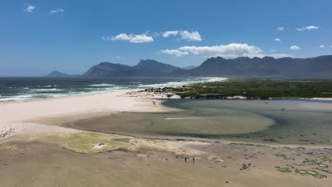 Person-kitesurfing-on-shallow-waters-near-South-Africa-coastline,-aerial-distance-view