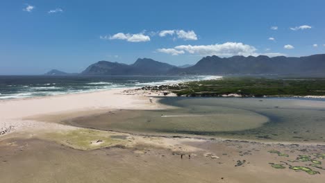 persona practicando kitesurf en aguas poco profundas cerca de la costa sudafricana, vista aérea a distancia