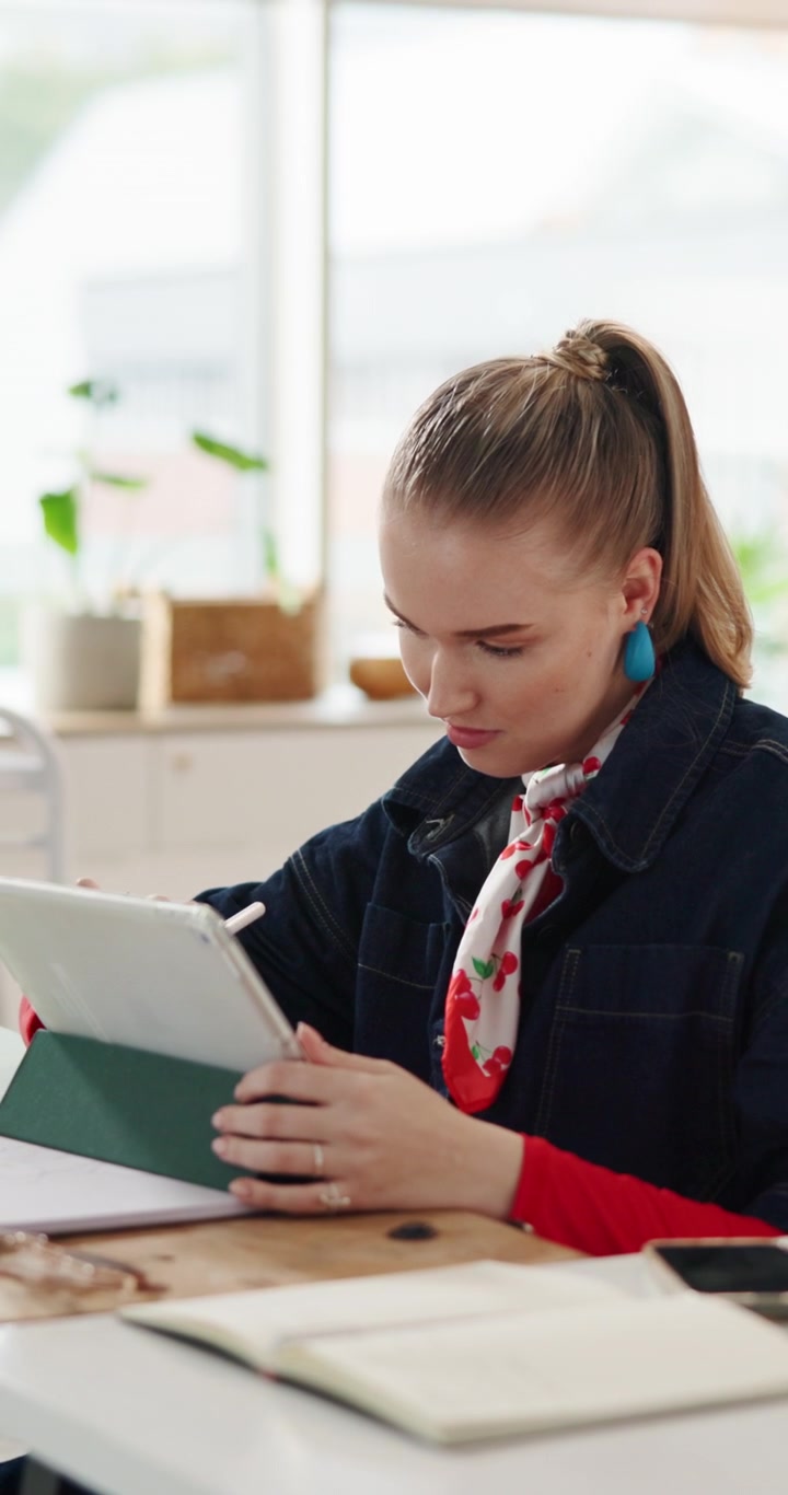 Ung kvinde bruger digital tablet med pen i et lyst kontor