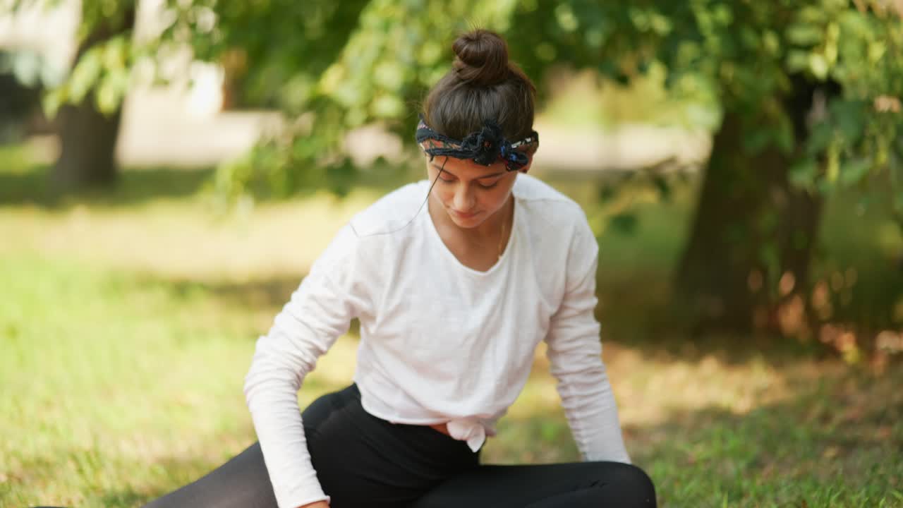 una mujer joven haciendo yoga en un parque.