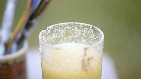 sumergir y golpear el pincel de pintura en el vidrio de agua de cerca
