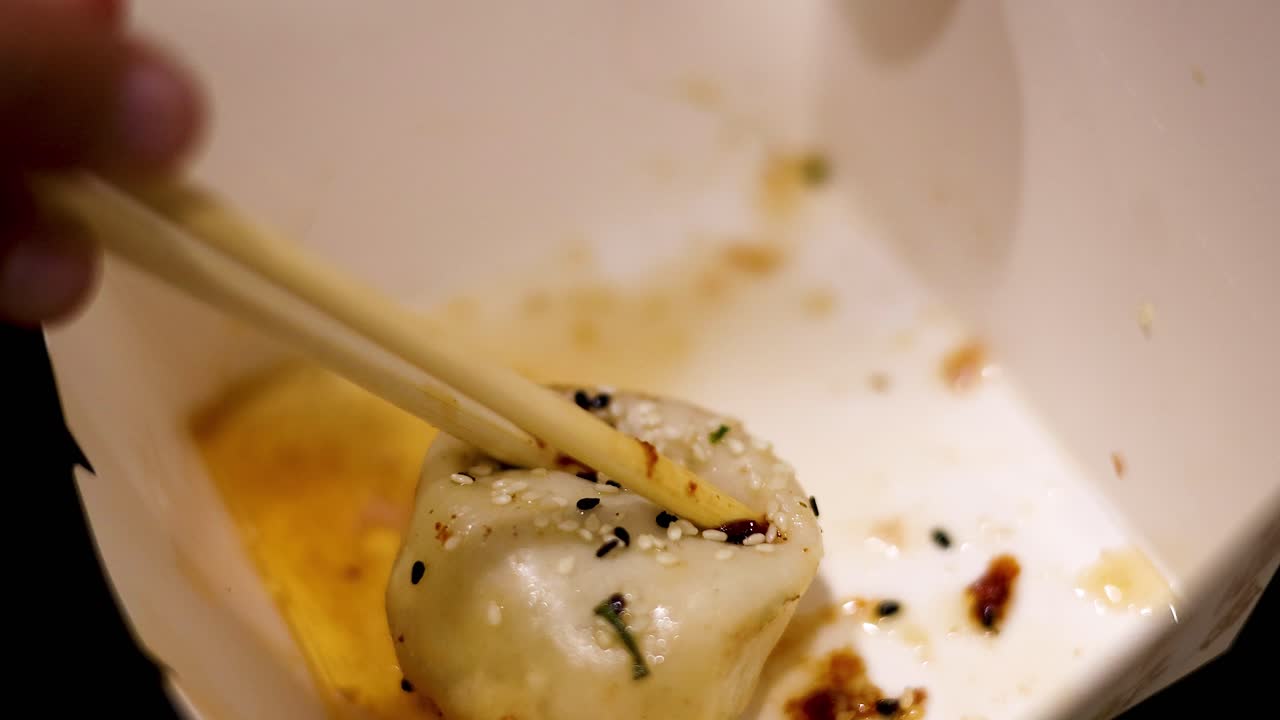 Chopsticks picking up a pan-fried bun