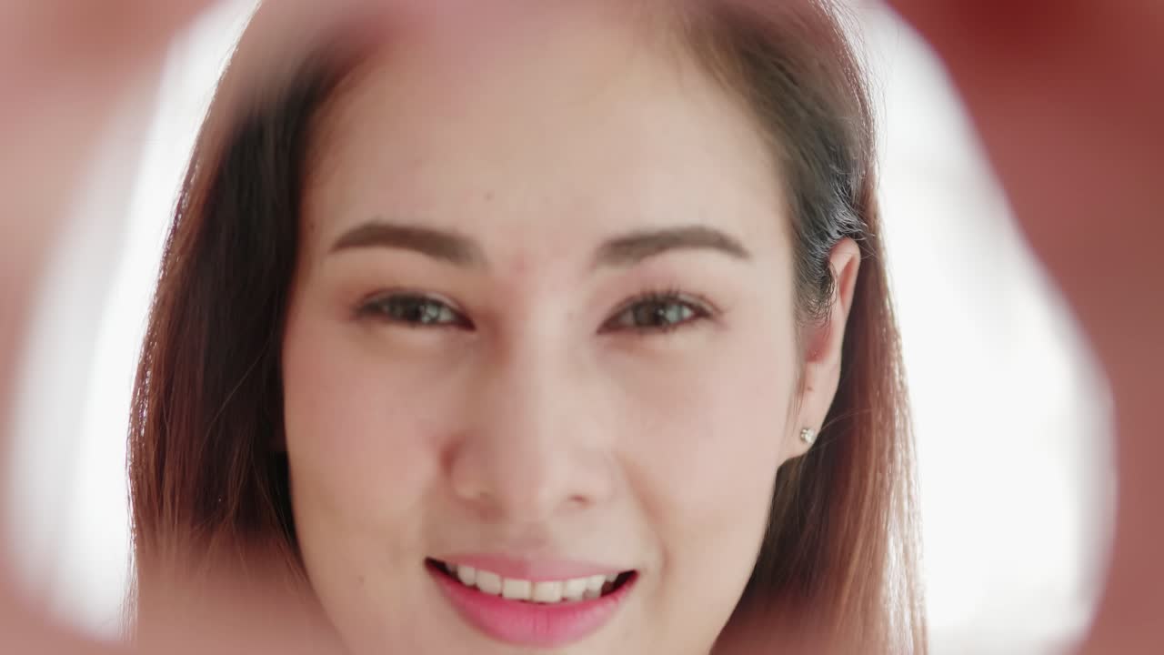 사랑스러운 아름다운 아시아 여성이 손 하트 모양으로 웃고 매우 행복합니다.