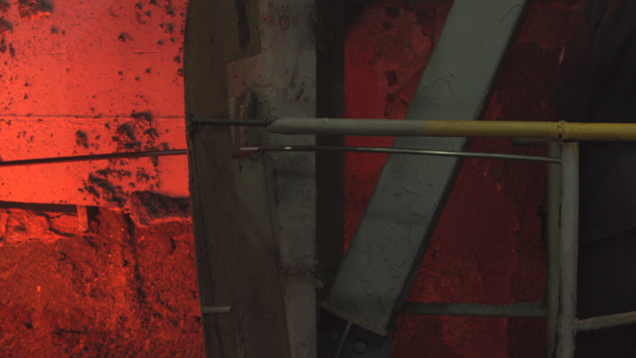 Industrial Worker Operating Tool in Hot Steel Mill Environment