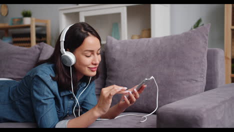 woman relaxing on couch, listening to music on smartphone