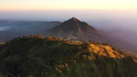 Dramatic-aerial-view-of-a-beautiful-mountain-range-surrounded-by-clouds-during-sunrise