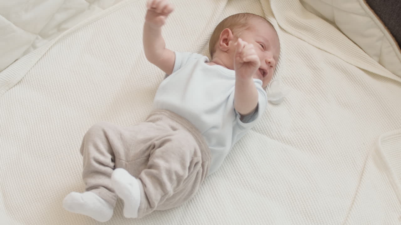 Cute Newborn Baby Lying On Bed And Crying 1