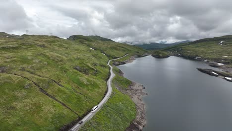 Bus-and-two-cars-crossing-Norwegian-Vikafjell-mountain-pass-beside-lake---Stunning-aerial-view-of-mountain-with-road-leading-to-Vik-in-Sogn-Norway