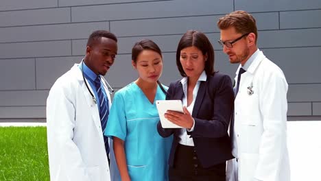 team of doctors discussing over digital tablet