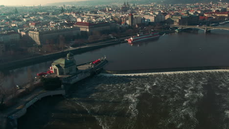 Vuelo-De-Drones-Sobre-El-Río-Vlatava-De-Praga-Que-Muestra-Puentes-Parque-Del-Castillo-Y-Edificios-Sol-De-Invierno