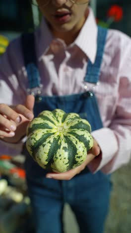 persona que sostiene una pequeña calabaza decorativa