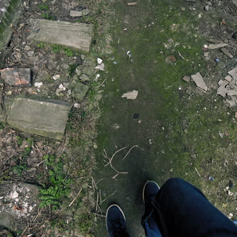 legs of a man going on the path near the old railroad outdoors. male's legs go through the dirty place with rubbish.