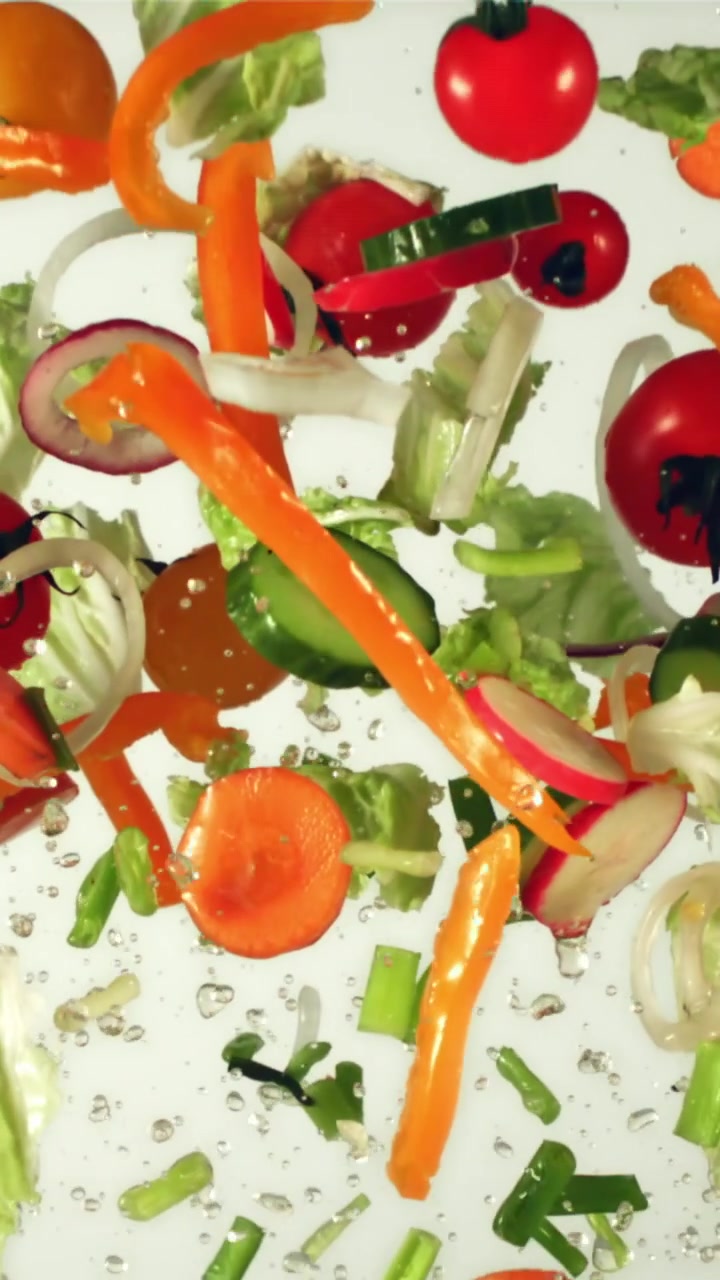 Verdure fresche tagliate che cadono e galleggiano nell'acqua
