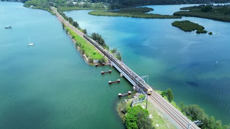 Drone-Aéreo-Tren-Cruzando-Puente-Vías-De-Ferrocarril-Línea-Gosford-Frente-Al-Mar-Narara-Creek-Mar-Río-Pantano-Transporte-Viaje-Costa-Central-Australia