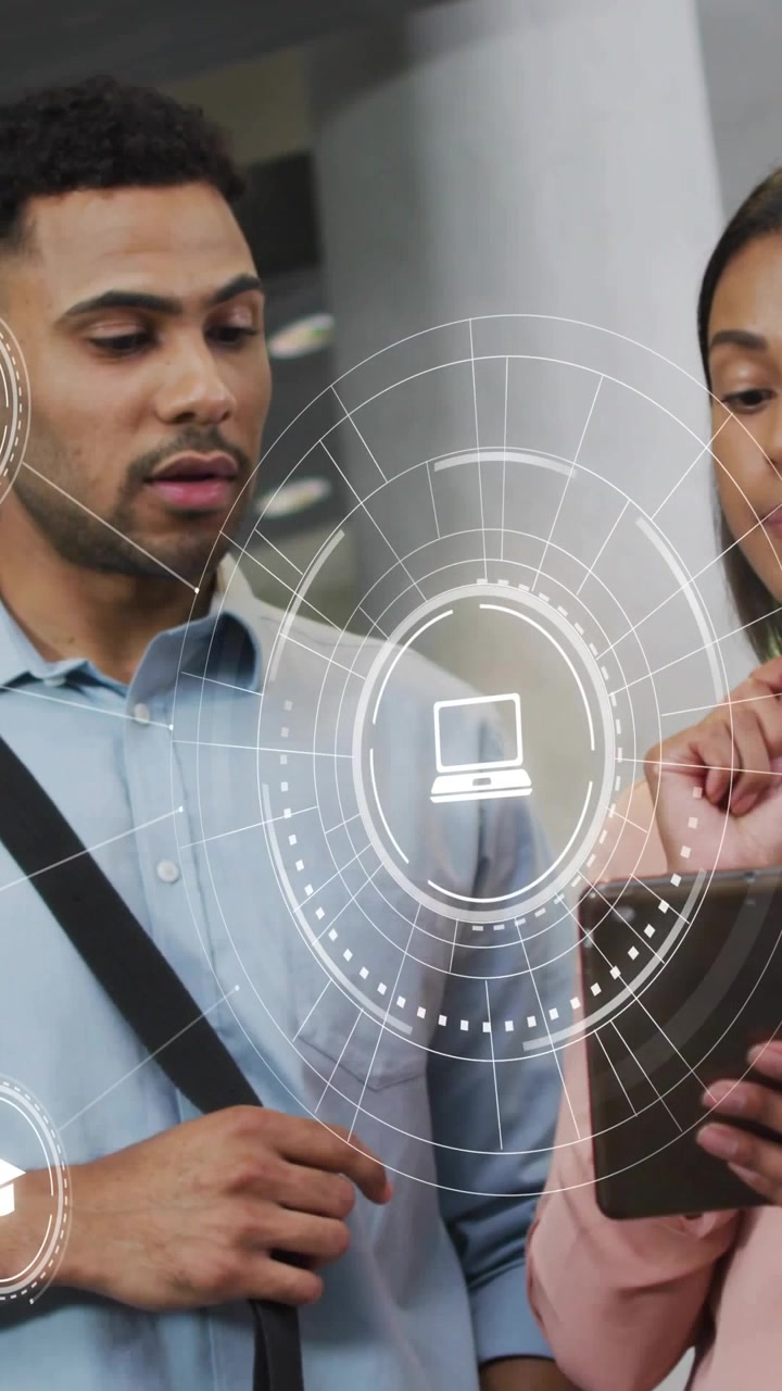 Vertical video: Woman tapping tablet and man pointing, HUD laptop icon showing data for business