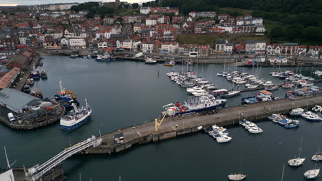 establishing drone shot of scarborough harbour with fishing boat entering harbour