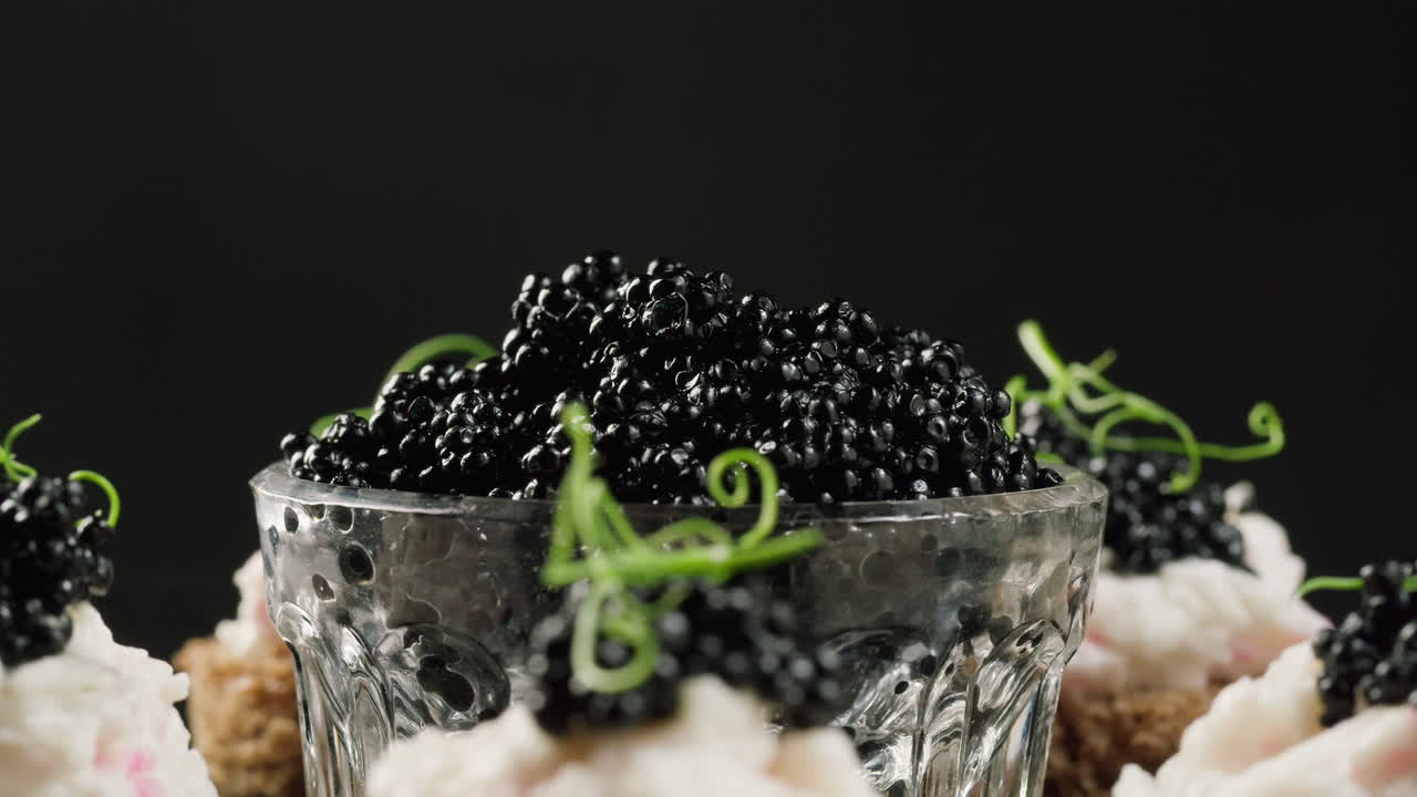 Caviale nero gourmet e tartine che ruotano su sfondo scuro