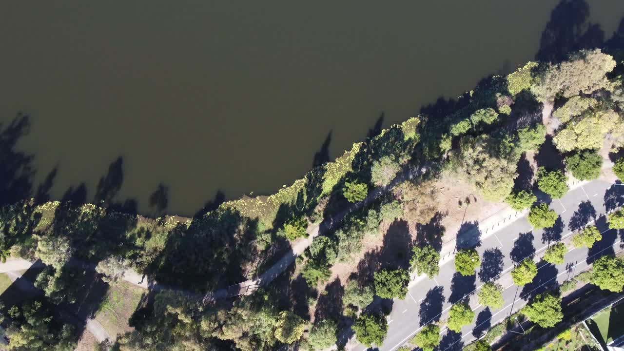 오스트레일리아 교외의 분할 된 도로의 공중 사진, 그 다음 인공 호수 위로 날아갑니다.