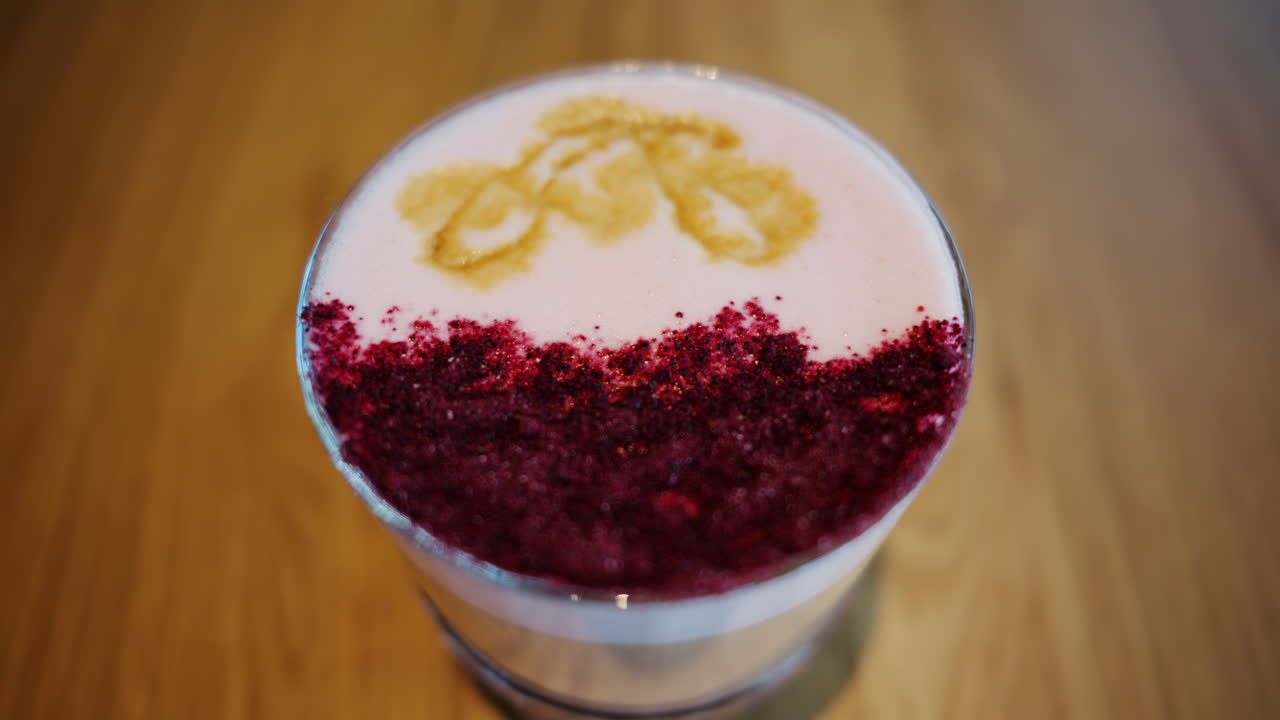Close up of a latte with pink decoration on top on a wooden table