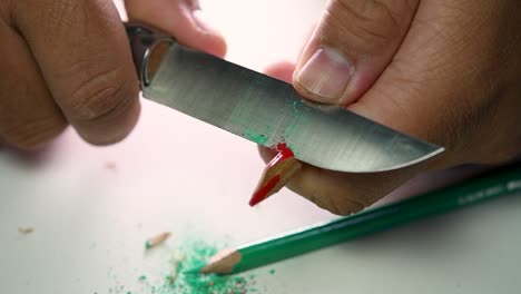 Footage-of-hands-slowly-sharpening-a-pencil-and-some-coloured-pencils-with-a-sharp-knife