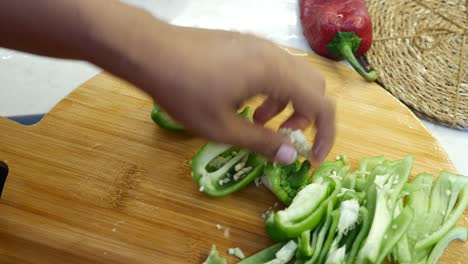 hands chopping a green pepper on a cutting board