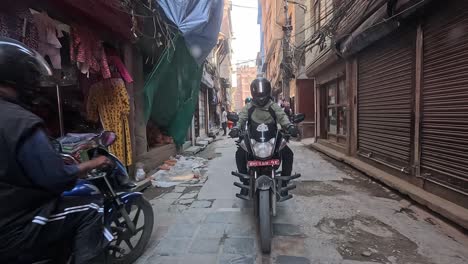 backseat view of a car navigating the lively alleys of central kathmandu, following motorbikers in a dynamic urban commute. thamel area full of stores and narrow alleys