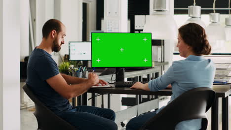 Startup team looking at pc greenscreen