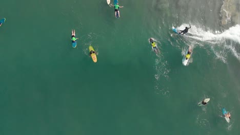 vertical aerial footage showing beginners and advanced level surfers,on their surf boards,surfing on water