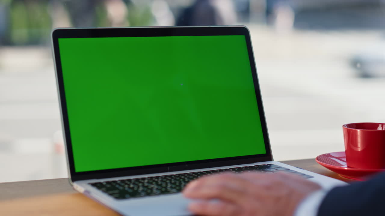 Dita di un uomo d'affari che scorrono sul touchpad di un mockup di laptop mentre lavora in un bar, primo piano