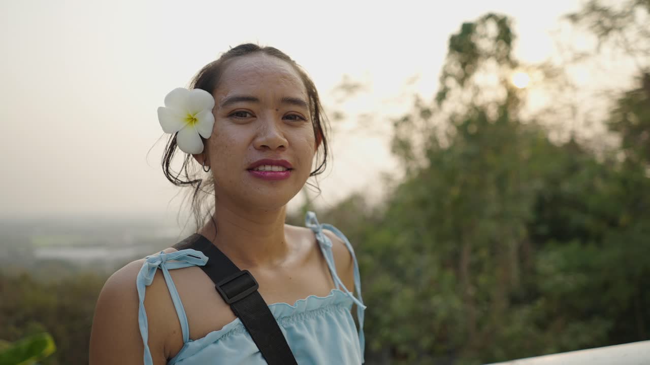 Woman with a tropical flower enjoying a scenic view