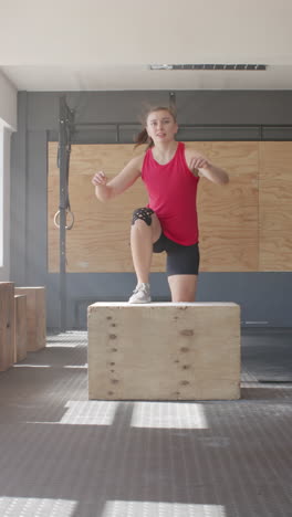 vertical video of portrait of caucasian sportswoman exercising with box at gym in slow motion