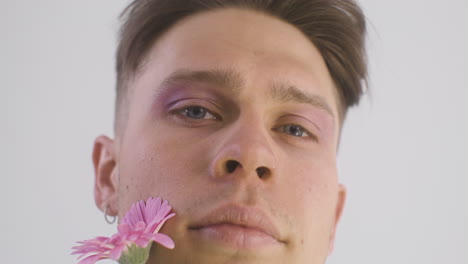 primer plano del hombre modelo sonriendo, sosteniendo una flor y mirando al frente