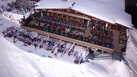 aerial drone video of crowded ski restaurant with terrace full of people