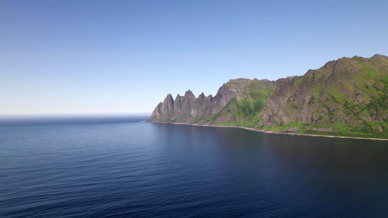 Drone flying over bay towards mountainrange on Senja in northern norway