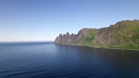 drone flying over bay towards mountainrange on senja in northern norway