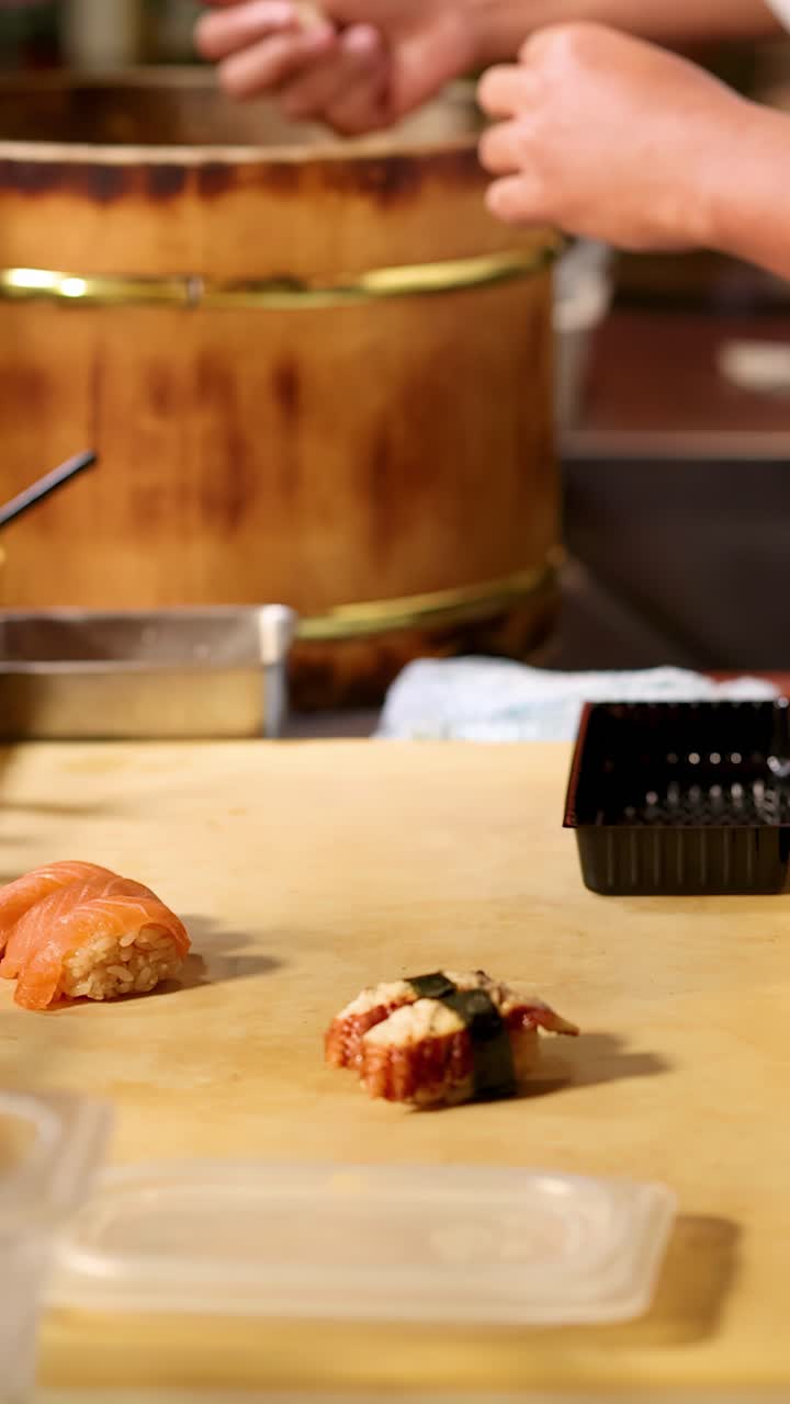 Um chef profissional prepara meticulosamente nigiri fresco de salmão e unagi em um balcão de madeira