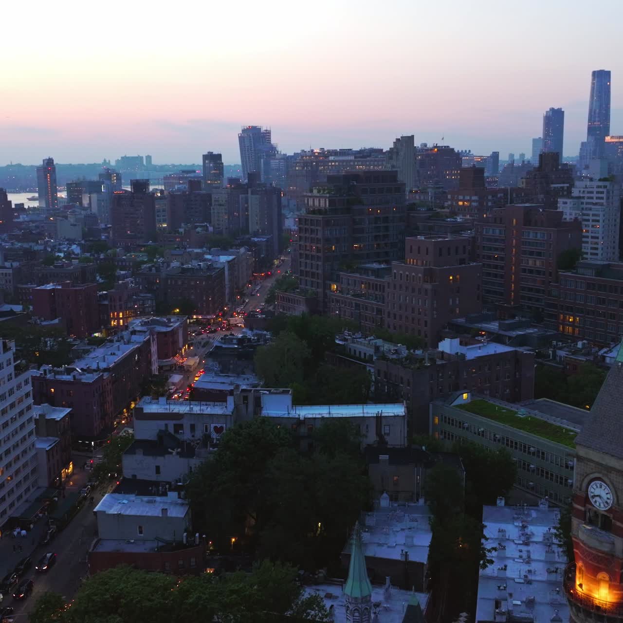 Evening New York starting to light lights at dusk. Avenues with multiple cars moving by. Skyscrapers at backdrop