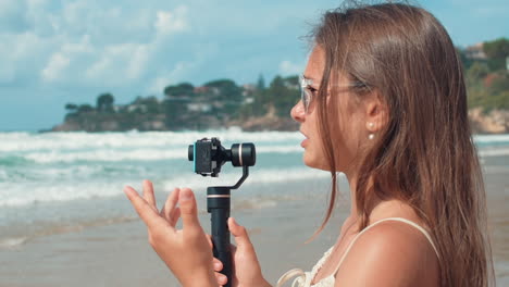 chica vlogger feliz filmando en la orilla del mar. mujer joven hablando con la cámara al aire libre.